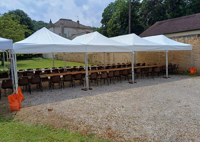 Trois barnums pliants 3x6 blancs alignés pour couvrir un repas en plein air avec tables et chaises, lors d'un événement convivial en extérieur