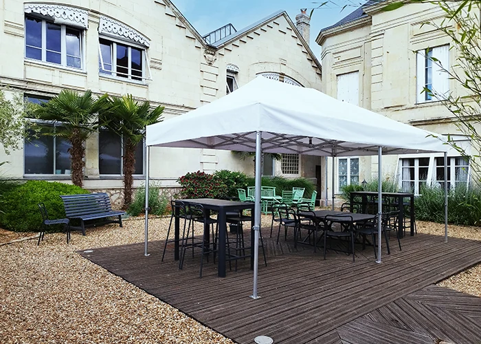 Barnum pliant 3x6 blanc installé dans une cour intérieure de bâtiment, avec tables et chaises, pour un usage professionnel ou événementiel