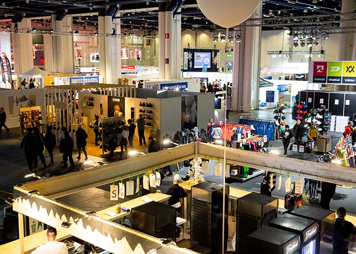 Visiteurs circulant dans l'allée d'un salon professionnel entre les stands exposants