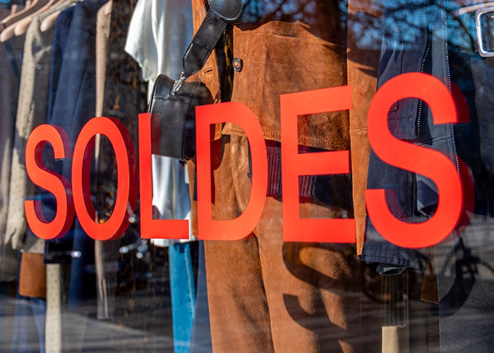Affichage "SOLDES" en lettres rouge vif sur une vitrine de prêt-à-porter, illustrant l'effet de la couleur rouge sur la perception des promotions et des prix